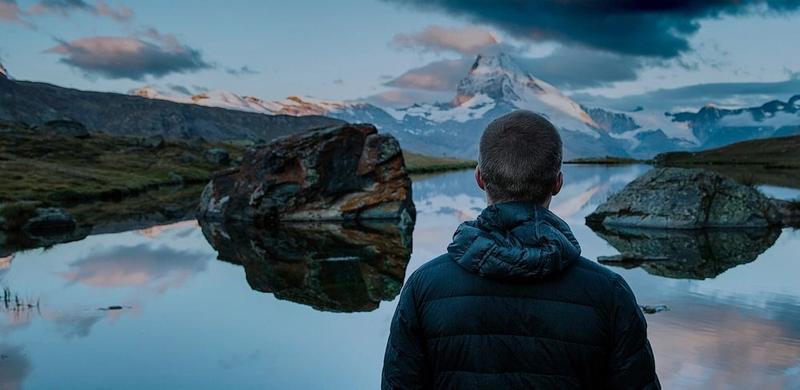 A man looks across a scenic lake view.